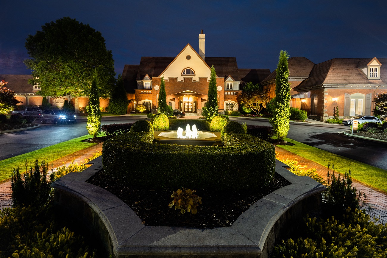 front of home with water fountain, shrub landscaping and outdoor lighting